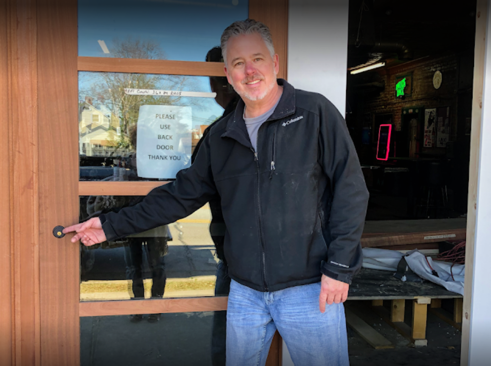 A man standing in front of a door with his finger pointed to lock